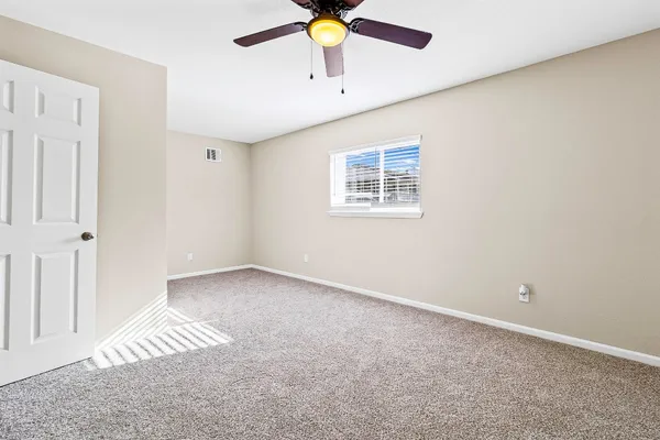 an empty room with a window and a ceiling fan