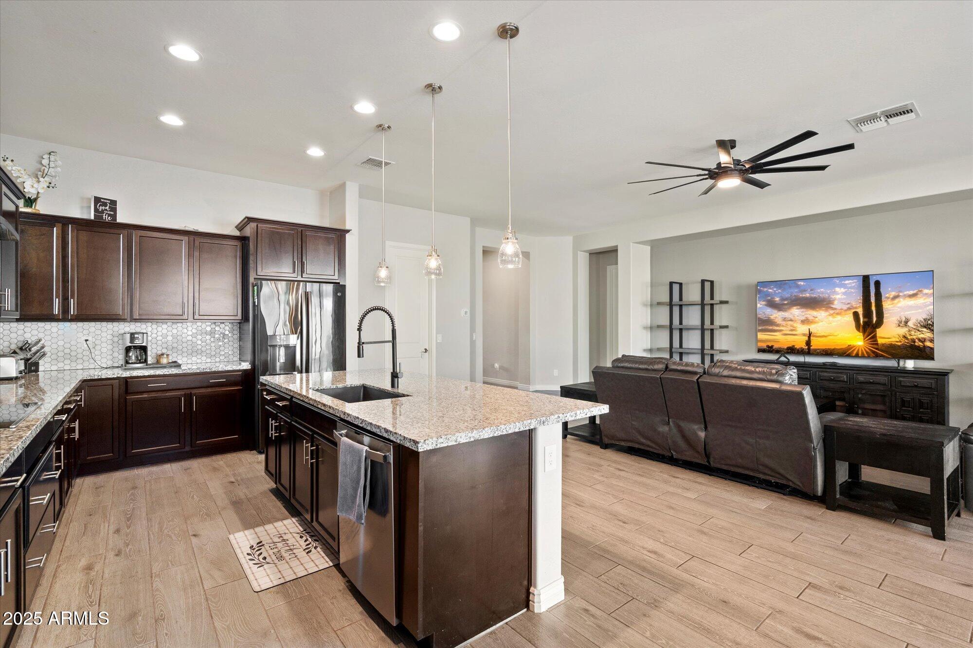 7424 West Jasmine Trail Peoria, AZ 85383 - Photo 8 of 30 a large kitchen with stainless steel appliances a stove a sink dishwasher and a refrigerator with wooden floor