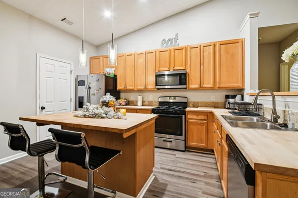 a kitchen with kitchen island granite countertop a sink a stove a counter top space and cabinets