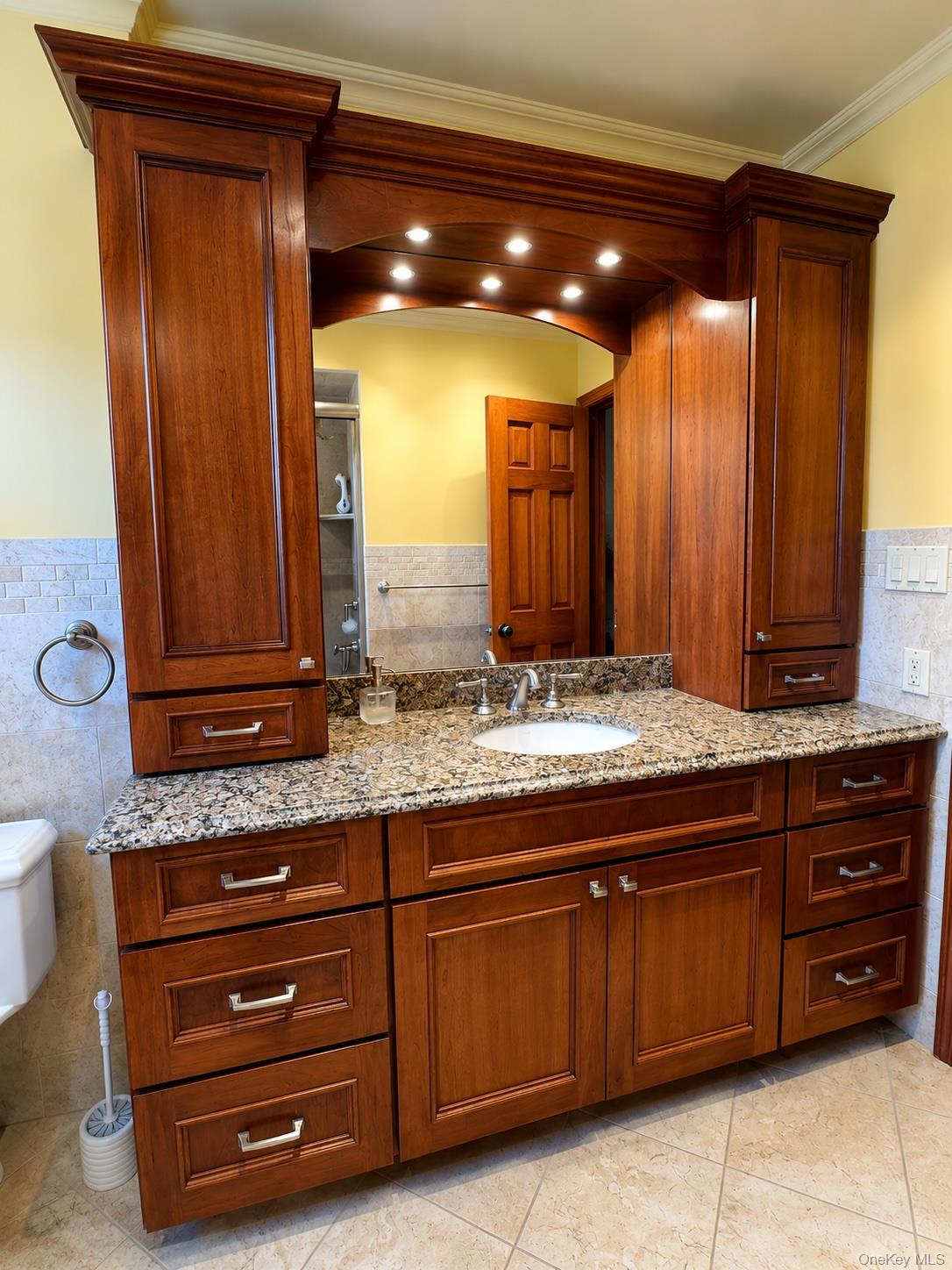 16 Clay Pitts Road Greenlawn, NY 11740 - Photo 11 of 25 Custom vanity featuring cherry-toned cabinetry, granite countertop, undermount sink, and integrated overhead lighting