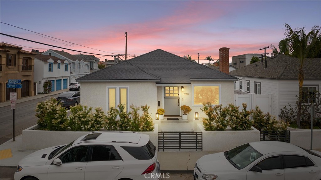a view of a white house with a small yard and potted plants