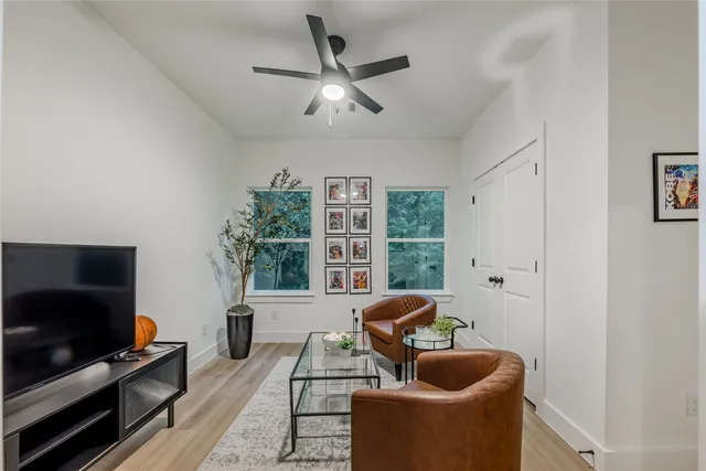 a living room with furniture a flat screen tv and a large window