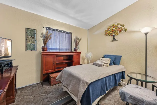 a bedroom with a bed and a flat tv screen on dresser
