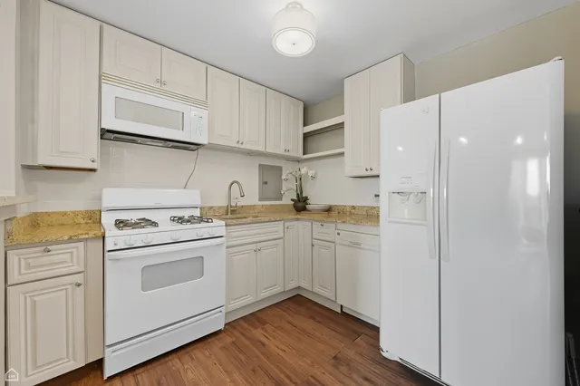 a kitchen with cabinets appliances wooden floor and a view of kitchen