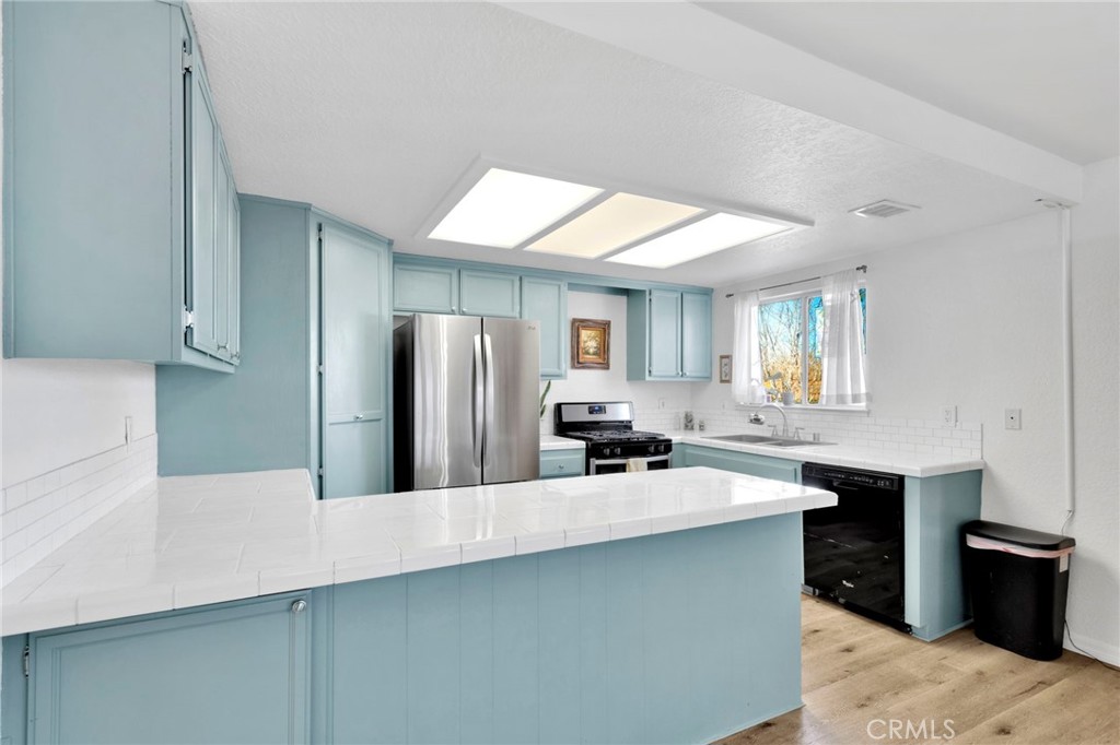 12655 Pocono Road Apple Valley, CA 92308 - Photo 15 of 52 a kitchen with stainless steel appliances a sink a stove a refrigerator a center island and cabinets