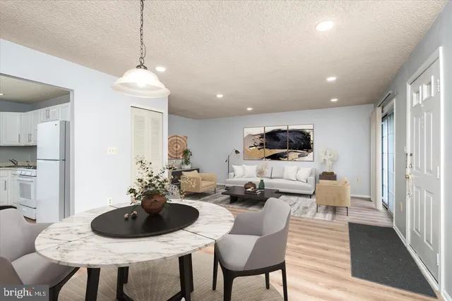 a living room with furniture kitchen view and a wooden floor