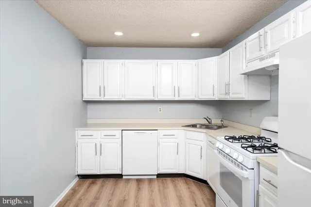 a kitchen with a white stove top oven and white cabinets