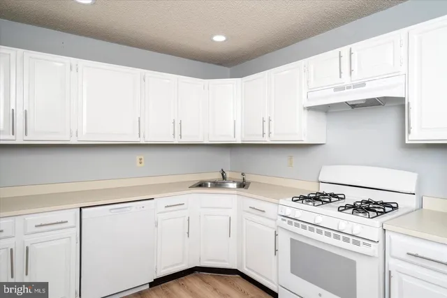 a kitchen with granite countertop white cabinets and white appliances