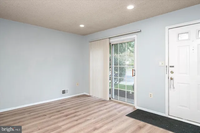 an empty room with wooden floor and windows