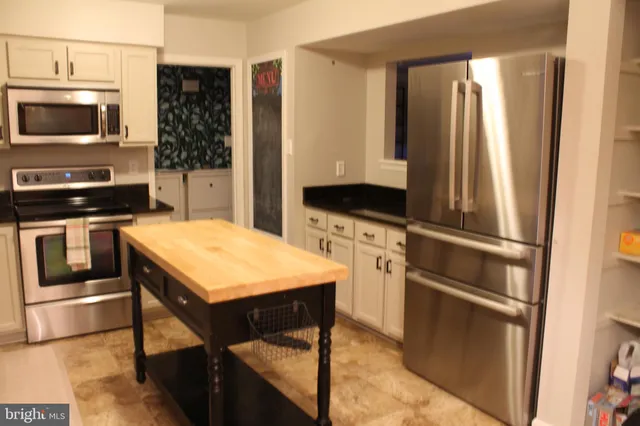 a kitchen with stainless steel appliances kitchen island granite countertop a stove top oven a sink and a microwave