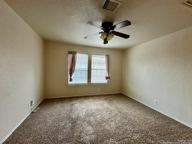 a view of a livingroom with a ceiling fan and kitchen view