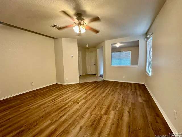 a view of an empty room and chandelier fan