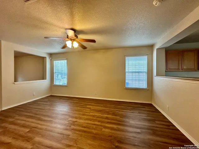 a view of an empty room with window and wooden floor