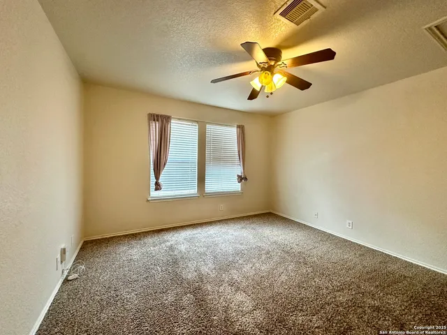 an empty room with a chandelier fan and windows
