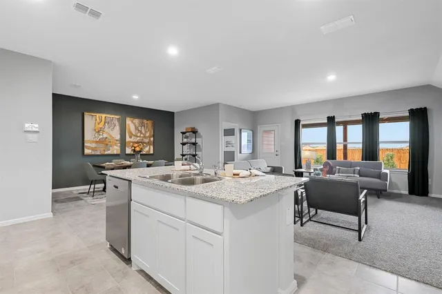 a living room with stainless steel appliances kitchen island granite countertop a sink and cabinets