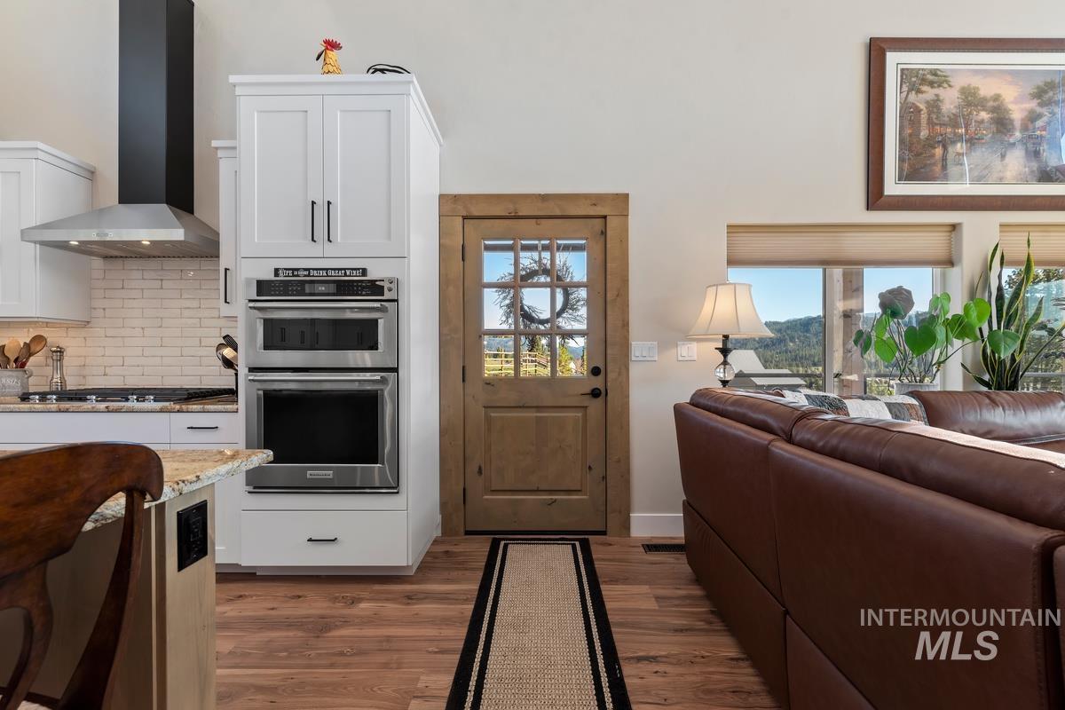 21 Open Road Garden Valley, ID 83622 - Photo 7 of 49 Kitchen with light stone countertops, stainless steel double oven, white cabinetry, dark wood-type flooring, and backsplash