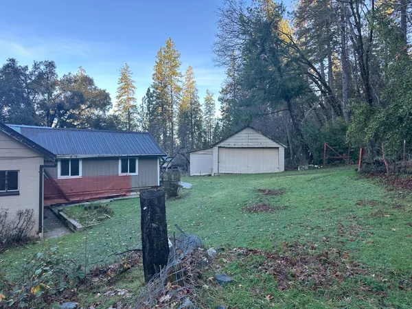 a view of a backyard with a barn and large trees