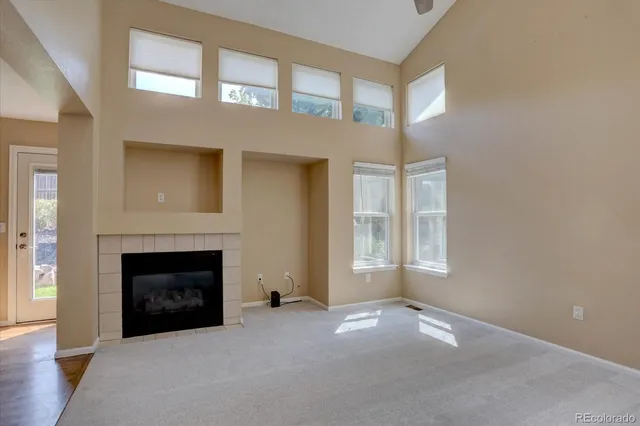 an empty room with windows and fireplace