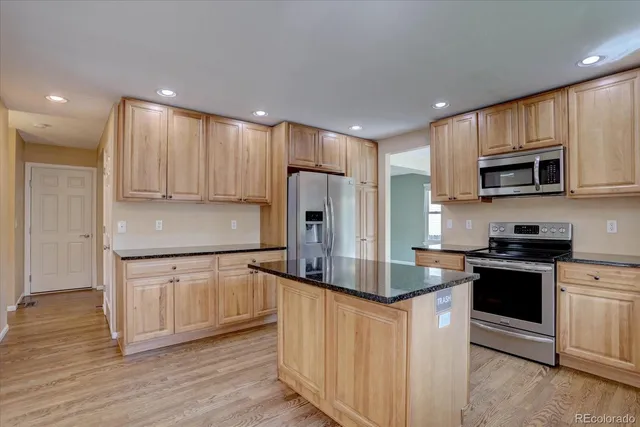 a kitchen with kitchen island granite countertop wooden cabinets and stainless steel appliances
