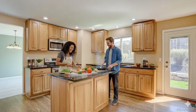 a kitchen with stainless steel appliances granite countertop a stove top oven a sink dishwasher and a refrigerator with wooden floor