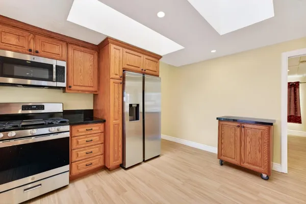 a kitchen with stainless steel appliances granite countertop a refrigerator stove and wooden cabinets