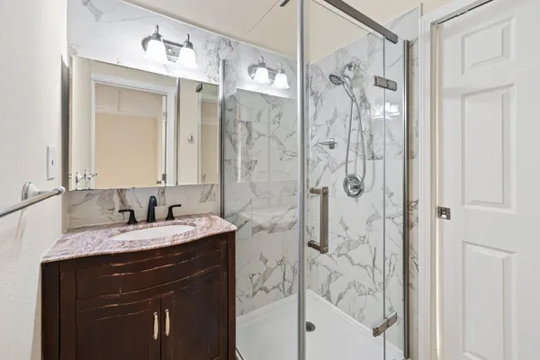 a bathroom with a bathtub shower sink vanity and mirror