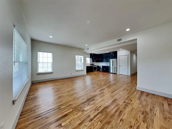 a view of empty room with kitchen and window