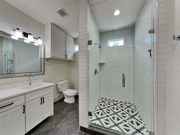 a spacious bathroom with a double vanity sink a toilet a mirror and shower