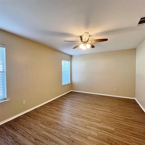 a view of an empty room with window and wooden floor
