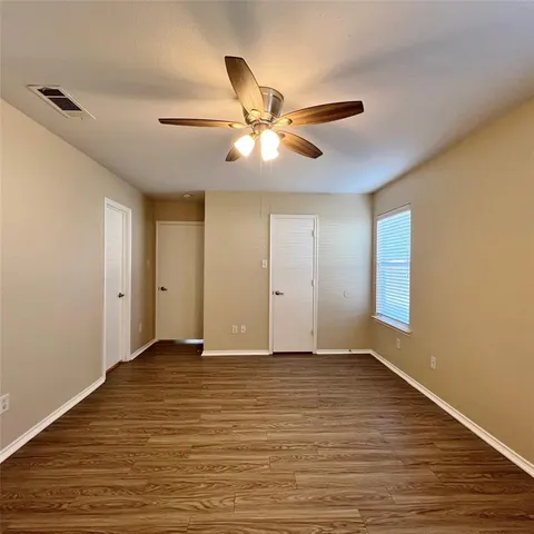 a view of an empty room with window and wooden floor