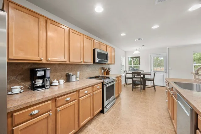 a kitchen with stainless steel appliances granite countertop sink stove top oven and cabinets