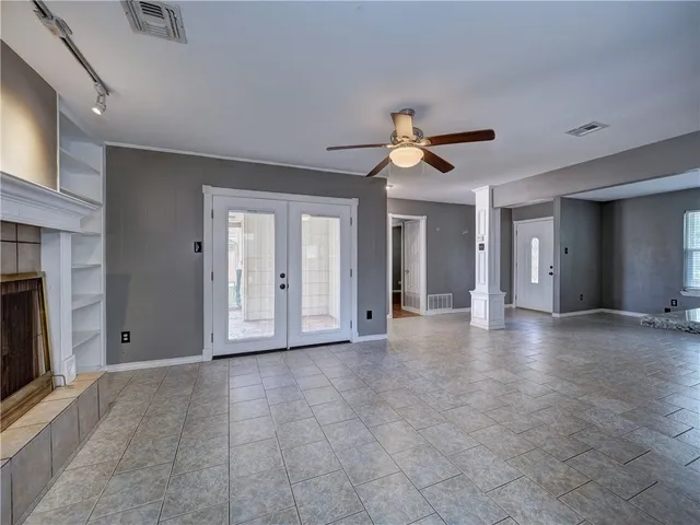 a view of a livingroom with a ceiling fan a fireplace and a large window