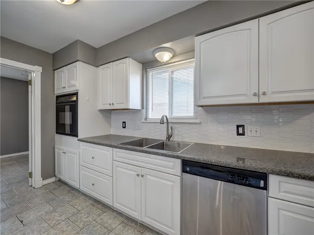 a kitchen with stainless steel appliances granite countertop white cabinets sink and dishwasher