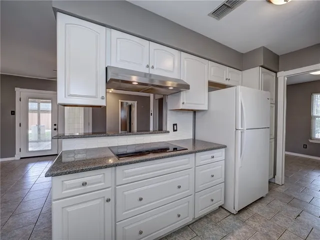 a kitchen with granite countertop white cabinets and refrigerator