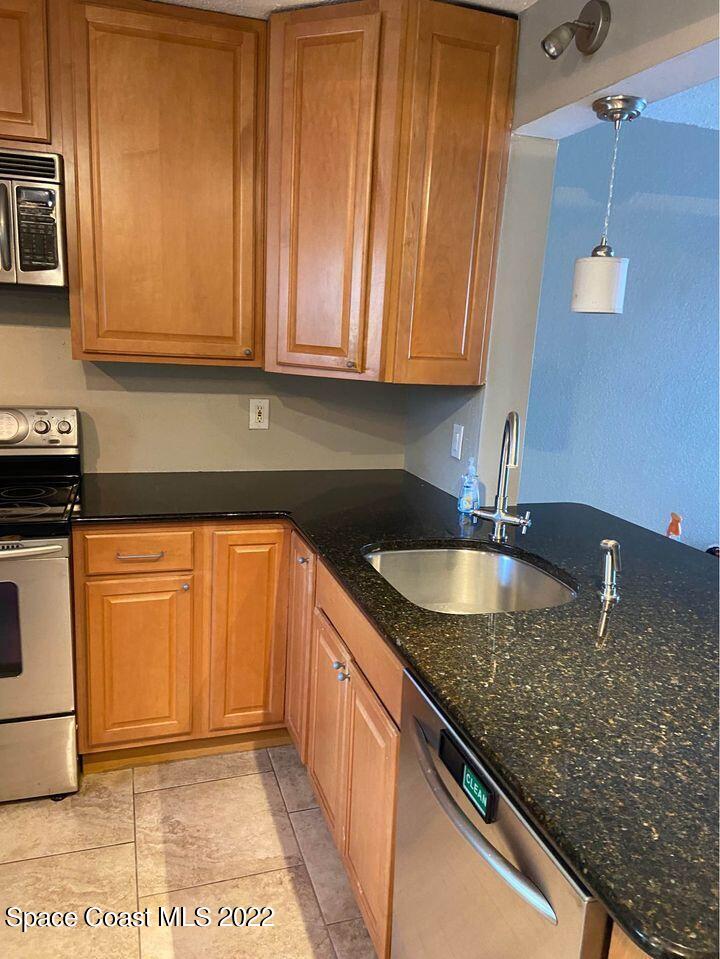 1611 Minutemen Causeway, Unit 207 Cocoa Beach, FL 32931 - Photo 6 of 11 a kitchen with granite countertop a sink a stove and cabinets