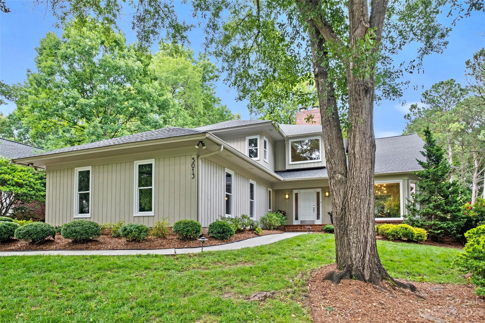 a front view of a house with a yard and trees