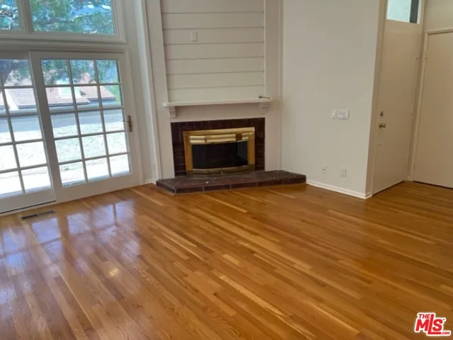 a view of an empty room with glass door and wooden floor