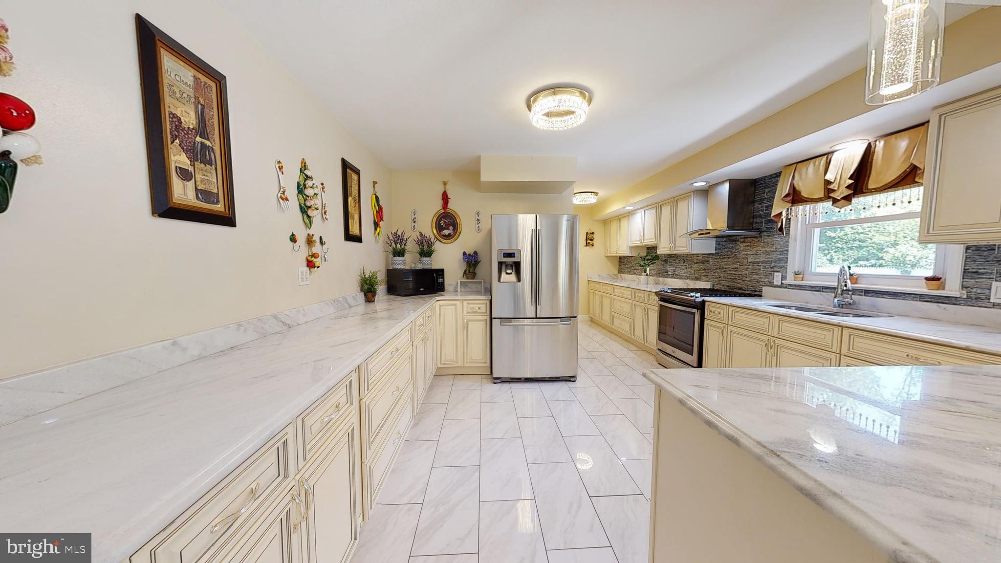 a large kitchen with kitchen island a large counter top space a sink a window and stainless steel appliances