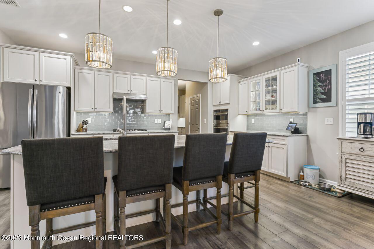 68 Harvest Ridge Road Howell, NJ 07731 - Photo 13 of 45 a kitchen with stainless steel appliances granite countertop a dining table chairs stove refrigerator and cabinets