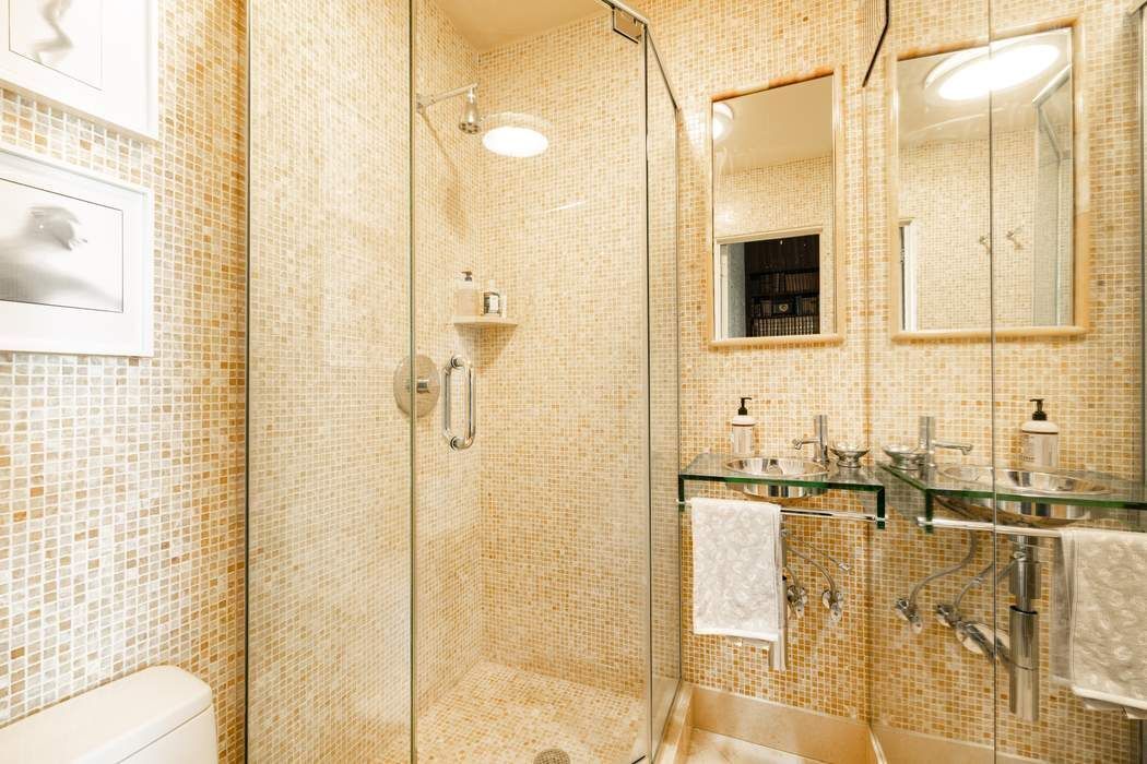 1010 5th Avenue, Unit 12F Manhattan, NY 10028 - Photo 11 of 17 a bathroom with a granite countertop shower a mirror and a sink