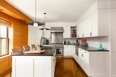a kitchen with stainless steel appliances granite countertop a sink stove and white cabinets with wooden floor