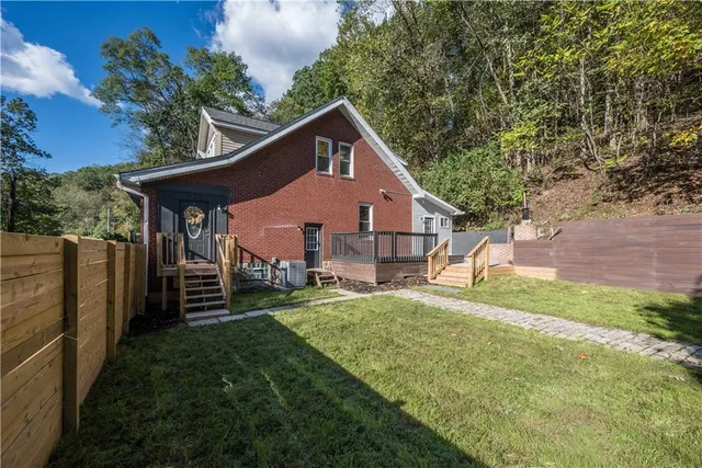 a view of a house with a yard potted plants and a large tree