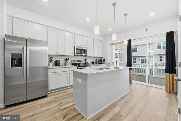 a kitchen with kitchen island a counter top space a sink stainless steel appliances and cabinets