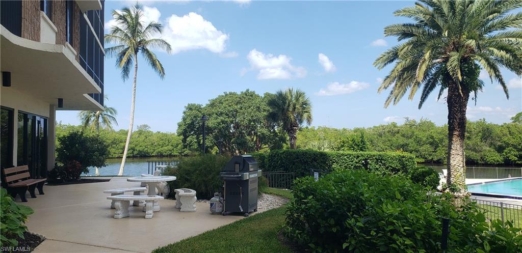 15 Bluebill Avenue, Unit 406 Naples, FL 34108 - Photo 15 of 18 a view of a patio with table and chairs potted plants and palm tree