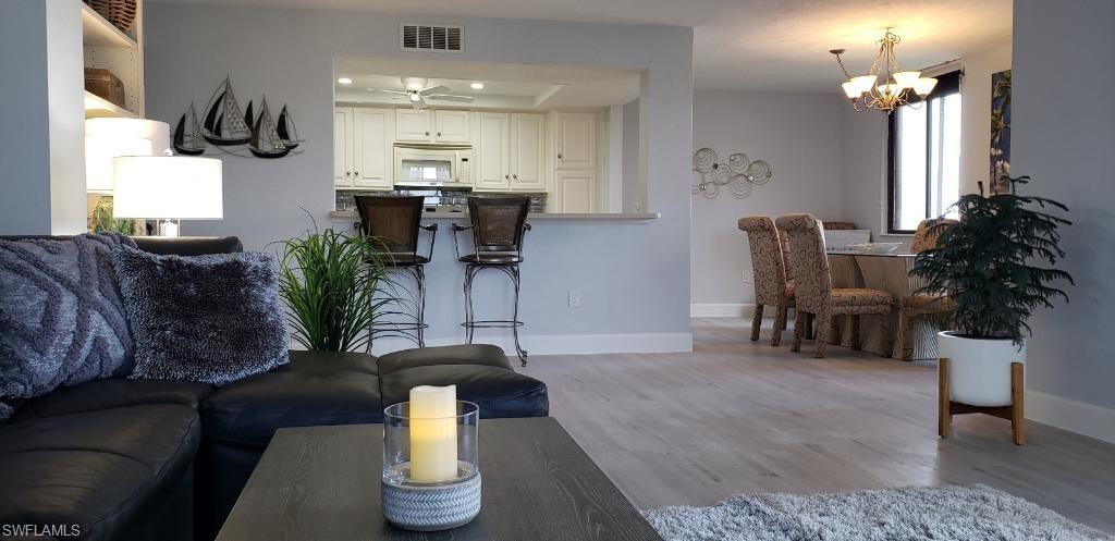 15 Bluebill Avenue, Unit 406 Naples, FL 34108 - Photo 4 of 18 a living room with furniture and a chandelier