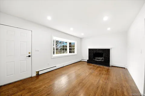 an empty room with wooden floor fire place and windows