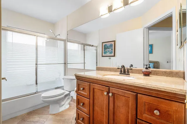 a bathroom with a granite countertop sink toilet a mirror and shower