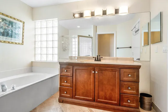 a bathroom with a granite countertop double vanity sink a mirror and a bathtub
