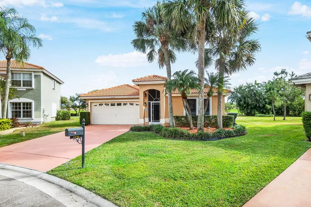 a view of a house with a yard and palm trees