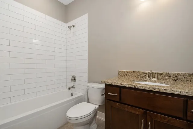 a bathroom with a granite countertop toilet sink and mirror